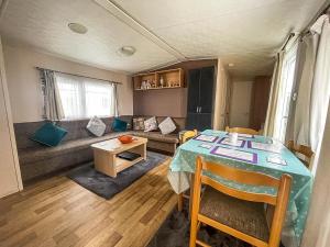 a living room with a table and a couch at Lovely 6 Berth Caravan At Oaklands Holiday Park Ref 39031cw in Clacton-on-Sea
