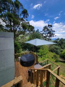 a wooden deck with an umbrella and a chair at EVA Glamping in Santa Elena