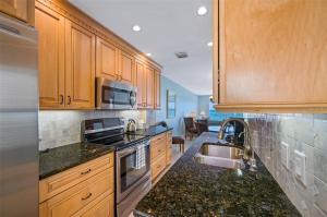 a kitchen with wooden cabinets and a sink at Oceanfront View of Madeira Beach, Steps to the Beach - Madeira Norte Condo in St Pete Beach