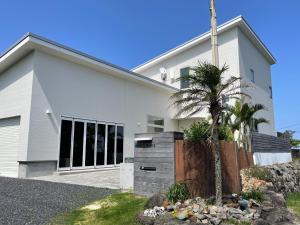 una casa blanca con una palmera delante de ella en MAISON DE AILE - Vacation STAY 58600v, en Amami
