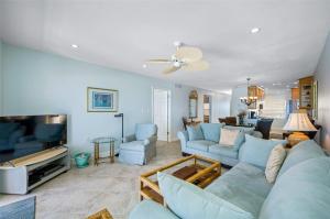 a living room with blue couches and a flat screen tv at Oceanfront View of Madeira Beach, Steps to the Beach - Madeira Norte Condo in St. Pete Beach