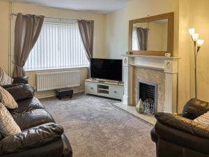 a living room with a television and a fireplace at Harris House in Staveley