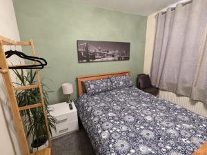 a bedroom with a bed with a blue comforter at Large Cosy Room to Stay in South Reading in Shinfield