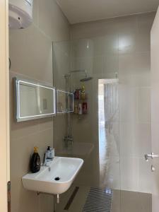 a white bathroom with a sink and a shower at Green Coast Resort Vila 143B in Dhërmi