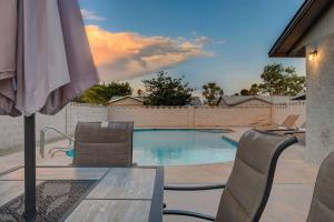 een zwembad met stoelen en een parasol bij Vegas Hideaway~Pool, Bar, Many beds~NEAR STRIP in Las Vegas