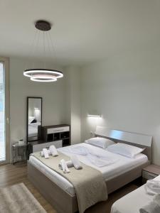 a white bedroom with two beds and a mirror at Green Coast Resort Vila 143B in Dhërmi