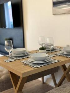 uma mesa de madeira com pratos e copos de vinho em Luxury 2 Bed Apartment - Near to Sherwood Forest em Ollerton