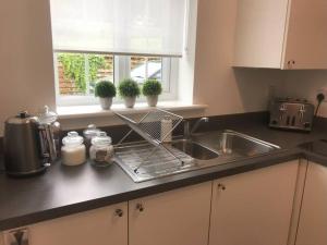 um balcão de cozinha com um lavatório e uma janela em Luxury 2 Bed Apartment - Near to Sherwood Forest em Ollerton