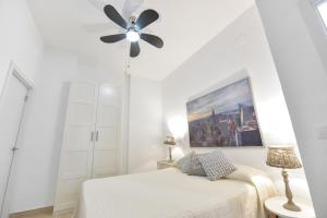 1 dormitorio blanco con ventilador de techo y 1 cama en Apartamentos Gran Vía, en Aracena