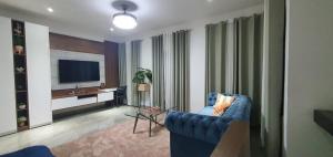 a living room with a blue couch and a television at The FJORD at Martsmith in Accra