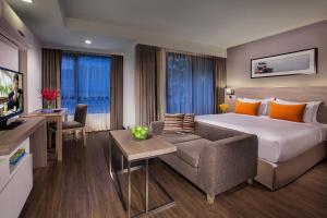 una camera d'albergo con letto e divano di Citadines Grand Central Sri Racha - SHA Extra Plus a Si Racha