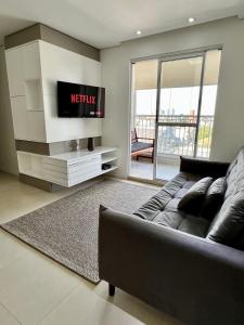 sala de estar con sofá y TV de pantalla plana en Conforto Expo Center Norte en São Paulo