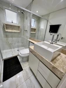 uma casa de banho branca com um lavatório e um WC em Conforto Expo Center Norte em São Paulo