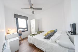 biała sypialnia z łóżkiem i oknem w obiekcie ApartamentosDnord w mieście Reus