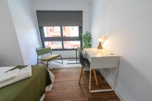 1 dormitorio con cama, escritorio y ventana en ApartamentosDnord, en Reus