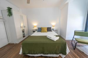 sypialnia z łóżkiem z zielonym kocem i krzesłem w obiekcie ApartamentosDnord w mieście Reus