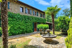 einen Brunnen vor einem Gebäude mit einer Palme in der Unterkunft Private villa with extensive gardens and pool in Lisciano Niccone