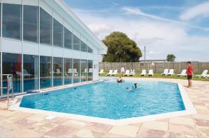 a group of people in a swimming pool next to a building at Happy Place in West Mersea