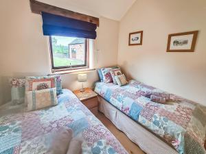 two beds in a room with a window at Bramble Barn in Tortworth