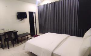 a bedroom with a bed and a table and a television at Hotel Matruchhaya - Near Lonavala Market Railway and Bus Station in Lonavala