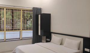 a bedroom with a bed and a window at Hotel Matruchhaya - Near Lonavala Market Railway and Bus Station in Lonavala