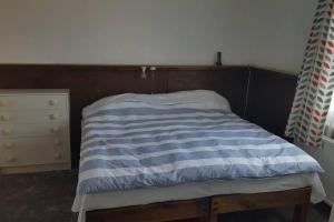 a bed with a blue and white striped blanket at Converted Bungalow In Bexley in Streatham Hill