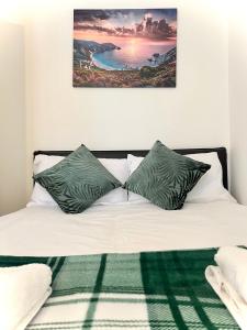 a bed with green and white pillows on it at White chapel Holiday 2 Bedroom Apartment in London