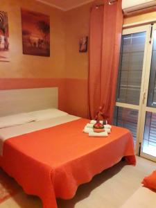 1 dormitorio con cama con sábanas de color naranja y ventana en Oasi Del Relax, en Civitavecchia