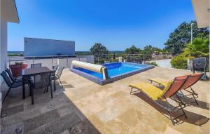 eine Terrasse mit einem Tisch und Stühlen sowie einem Pool in der Unterkunft Beautiful Home In Portiragnes With Kitchen in Portiragnes