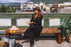 una mujer sentada en un banco leyendo un libro en First Hotel Breiseth en Lillehammer