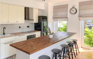 a kitchen with white cabinets and a counter with stools at 2 Bedroom Beach Front Apartment In Rydzewo in Rydzewo