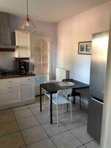 a kitchen with a table and chairs and a refrigerator at Villa Bonheur secteur Blagnac 9 pers Netflix Wifi in Mondonville