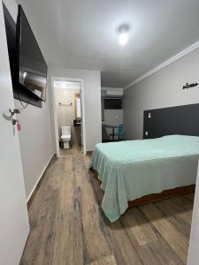 um quarto com uma cama e uma televisão de ecrã plano em Cobertura em Florianópolis
