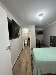 a hotel room with a bed and a flat screen tv at Cobertura in Florianópolis