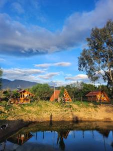a group of houses next to a body of water at Glamping El Muelle in Villa de Leyva