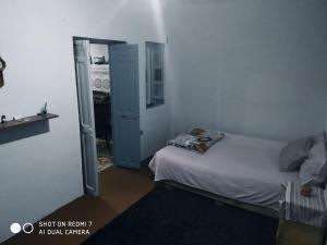 ein Schlafzimmer mit einem Bett und einer offenen Tür in der Unterkunft شفشاون in Aït Saïd