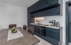 una cocina con armarios de color azul oscuro y una mesa con sillas. en 3 Bedroom Cozy Home In Dramalj, en Dramalj