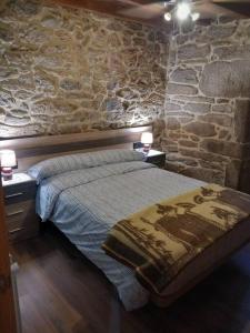 a bedroom with a bed and a stone wall at Casa de Crabera in A Coruña