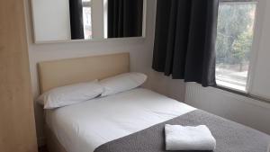 una piccola camera da letto con letto e specchio di 30 willesden lane a Londra