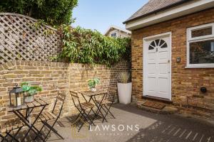 una casa de ladrillo con una puerta blanca y sillas en Loft Living by Lawsons en Windsor