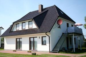 a white house with a black roof at Ferienwohnung am Dorfrand in Wieck