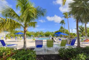 a pool with blue and green chairs and palm trees at 2306 Ocean Pointe in Tavernier