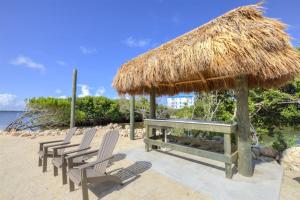 a table and chairs on a beach with a straw hut at 2402 Ocean Pointe in Tavernier