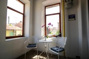 two chairs and a table in a room with two windows at City Center Rooms in Pula