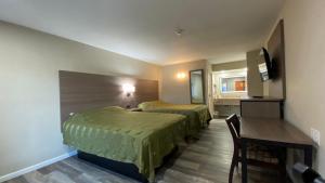 a hotel room with two beds and a desk at Brentwood Inn & Suites in Suffolk