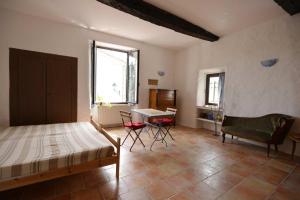 1 dormitorio con 1 cama, mesa y sillas en Studio de la cheminée et studio de la place en Sigonce