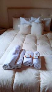 Una cama blanca con almohadas blancas y toallas. en Alojamiento Casa en Pilar en Pilar