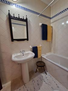 een badkamer met een wastafel, een bad en een spiegel bij Casa do Avô Lopes in Tomar