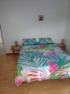 sypialnia z łóżkiem z kolorową kołdrą w obiekcie Vanylle Lodge w mieście Punaauia