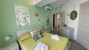 1 dormitorio con cama amarilla y paredes verdes en La Terrazza del Capo en San Vito lo Capo